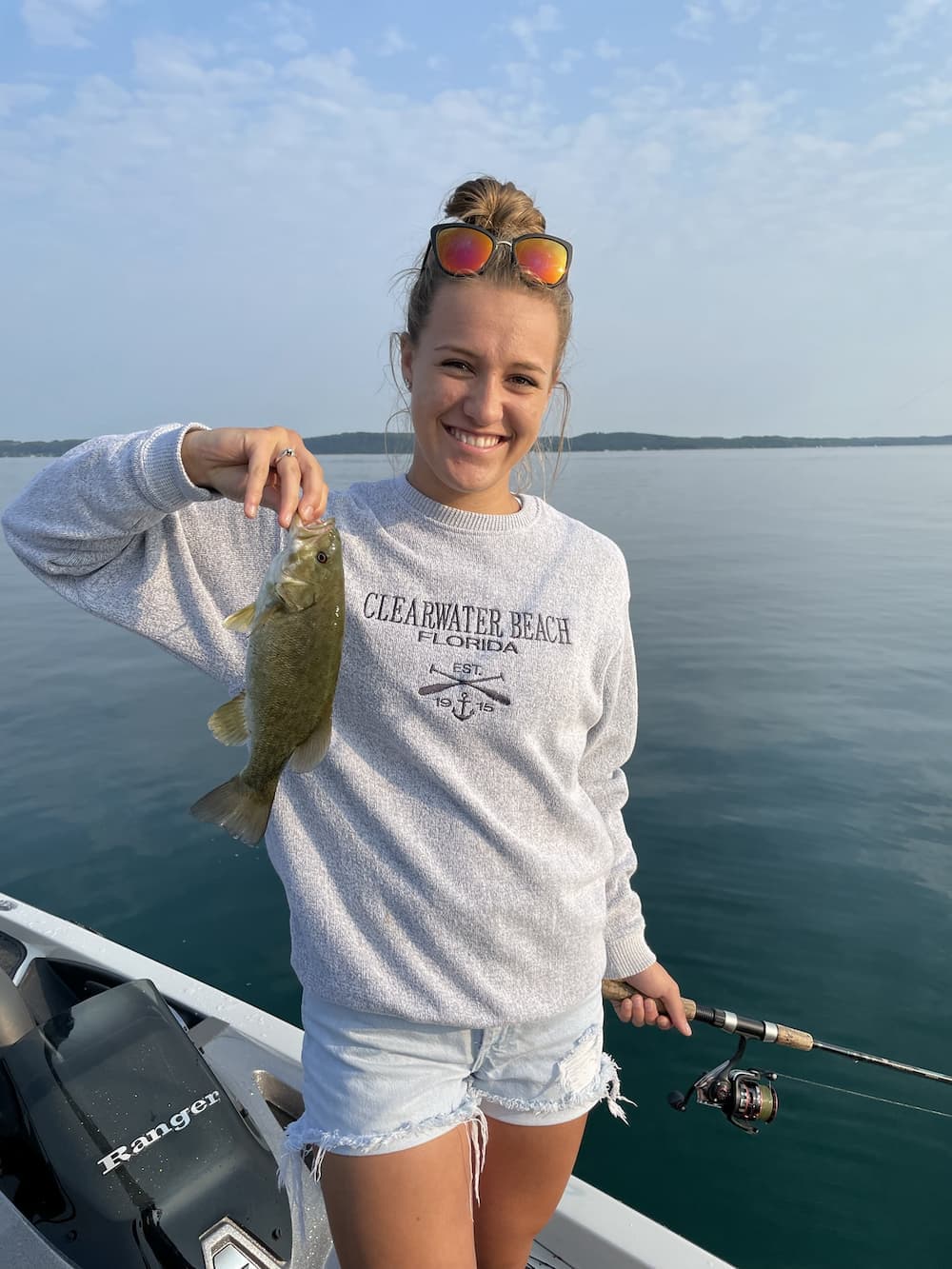 Woman with bass catch on calm water
